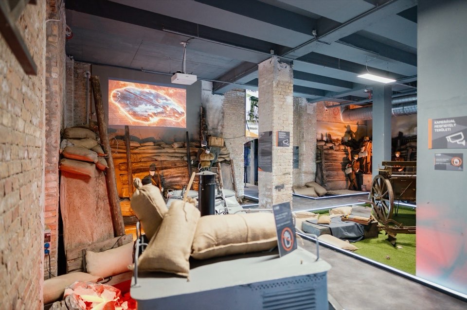 Exhibition interior with a sandbagged bunker set, a desk and seating.