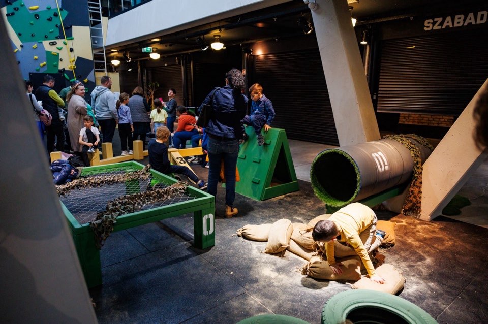 Visitors gathered around an interactive exhibition station with a training mannequin on the floor.