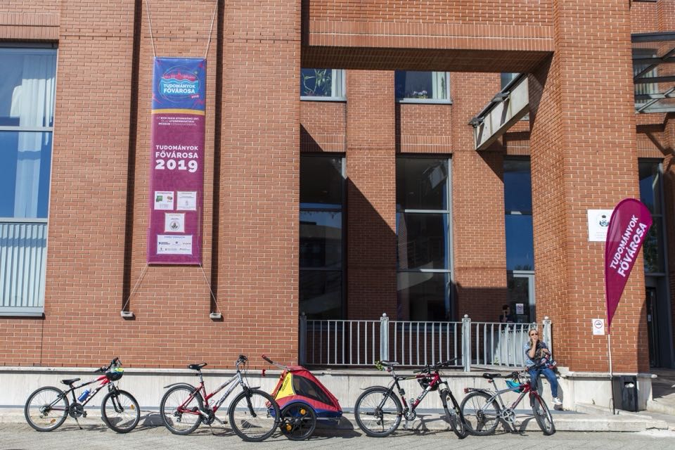 A brick university building with festival banners and bicycles parked in front.