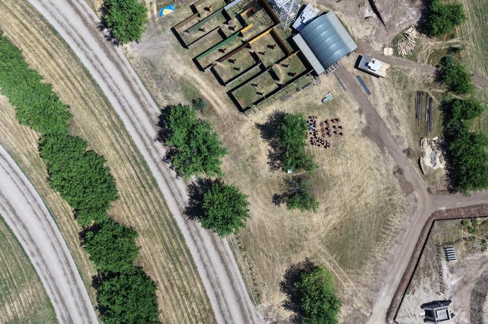 Aerial view of trench-style structures and buildings beside a railway line.