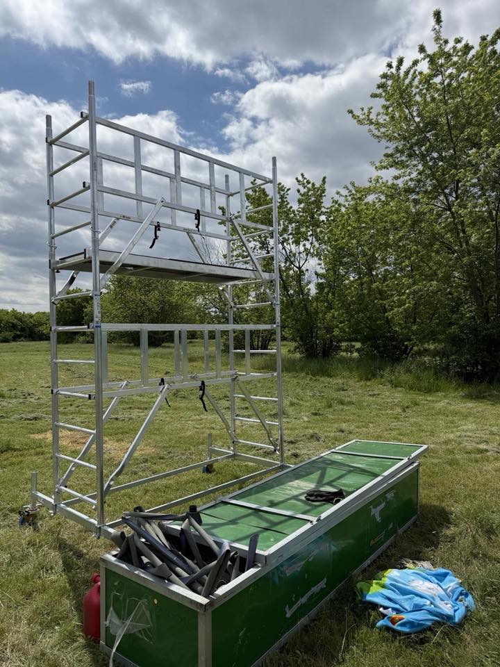 A mobile scaffold tower and an equipment crate on grass during set-up.