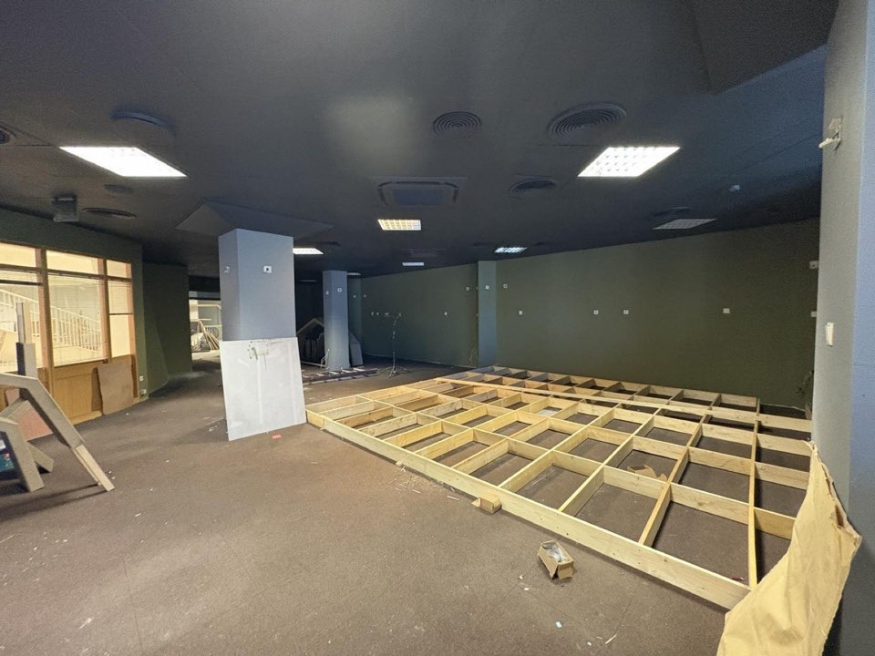 An empty interior during fit-out, with timber floor frames laid out across the room.